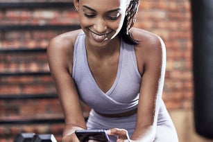 Joven deportista usando un teléfono móvil con pilates booking system Tecnofit